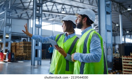 Factory workers discussing tablet information analysing production process. Uniformed professional manufacture supervisors checking modern device info inspecting. Tech partnership workplace concept - Shutterstock ID 2119544030