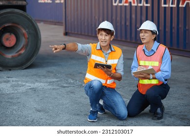 factory workers or engineers talking about project work and pointing to something in containers warehouse storage