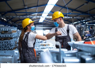 Factory Workers Greeting Each Others With Elbows During Corona Virus Pandemic. Industrial Employees Wearing Protection Masks Due To COVID-19 Infection.