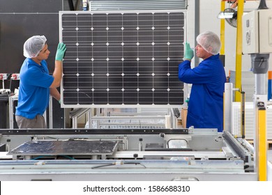 Factory Workers Lifting New Solar Panel From Production Line