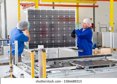 Factory Workers Lifting New Solar Panel From Production Line