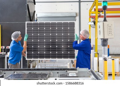 Factory Workers Lifting New Solar Panel From Production Line