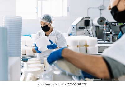 Factory workers preparing fresh cheese, ensuring food production hygiene