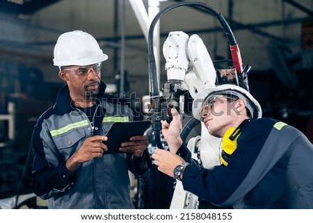 Factory workers working with adept robotic arm in a workshop . Industry robot programming software for automated manufacturing technology .