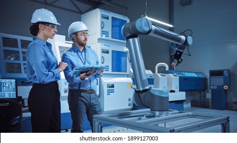 Factory Workshop: Professional Female Engineer, Male Machinery Operator Use Industrial Digital Tablet Computer to Work and Program Robot Arm for Production Line. High-Tech Facility with CNC Machines - Shutterstock ID 1899127003