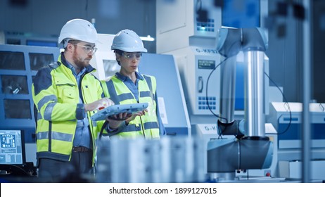 Factory Workshop: Professional Female Engineer, Male Machinery Operator Use Industrial Digital Tablet Computer to Work and Program Robot Arm for Production Line. High-Tech Facility with CNC Machines - Shutterstock ID 1899127015