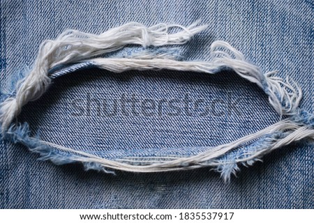 a faded blue demin background with a slit in middle,torn denim