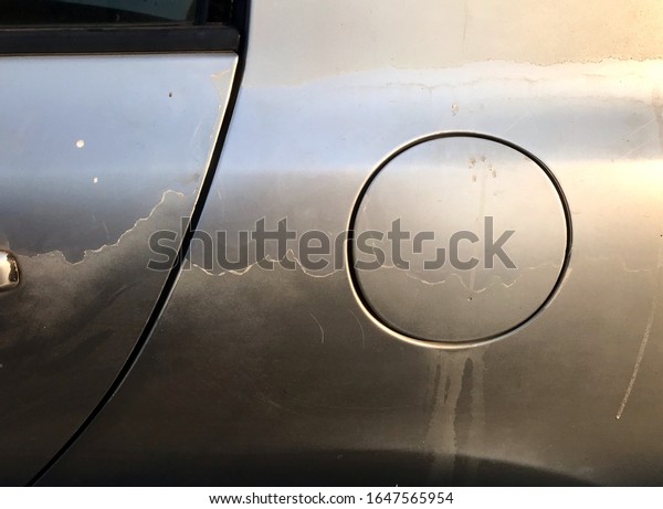 Faded car painting, close up gas tank cap, side\
view or car. Color coating damage from aging service and hot\
temperature weather.