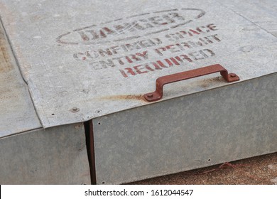 A Faded Danger, Confined Space Entry Permit Required Warning Sign On The Uplifing Door Of An Inground Grain Storage Bin