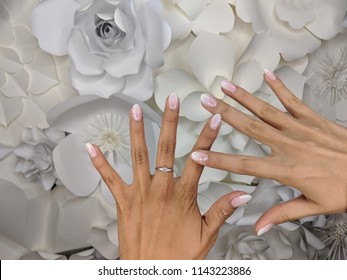 Faded Ombre French Nail Baby Boomer Manicure From Two Women Hands With Ring Against A White Floral Background