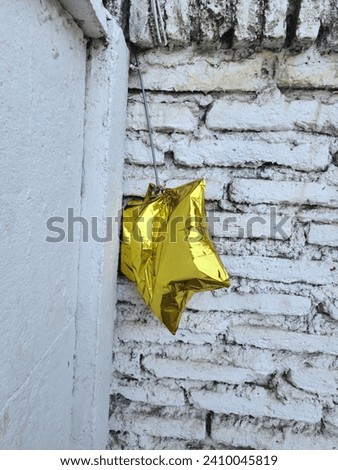 Faded Starlight: Semi-Deflated Yellow Star-Shaped Balloon, A Remnant of Celebration, Capturing the Whimsy of Festivity's End, Symbolizing the Ephemeral Beauty of Joyous Moments