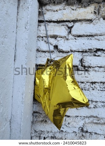 Faded Starlight: Semi-Deflated Yellow Star-Shaped Balloon, A Remnant of Celebration, Capturing the Whimsy of Festivity's End, Symbolizing the Ephemeral Beauty of Joyous Moments