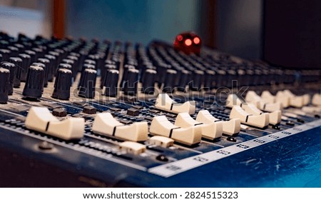 Faders and controls on an analog audio mixing console in a music recording studio