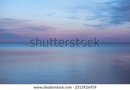 A fading pink and purple sunset over the lake on a peaceful evening in Toronto, Ontario, Canada. The blue colours of dusk make the scene look almost unreal.