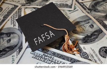 FAFSA (Free Application for Federal Student Aid) text on graduation cap and money -- financial aid concept                             