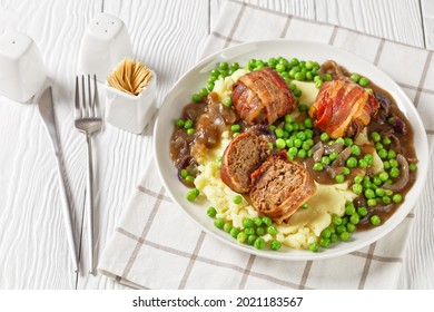 faggots, english meatballs with creamy mashed potatoes, green peas and rich, thick onion gravy on a white plate, classic british cuisine