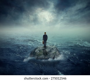Failure crisis concept and lost business career education opportunity. Lonely young man on a rock cliff island surrounded by an ocean storm waves 