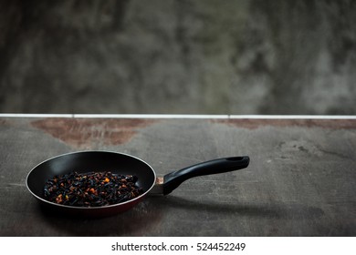 The Failure On Kitchen: Burnt Charred Vegetables. Frying Pan With Refried Black Onion And Overcooked Orange Carrots. Cooking Fail Concept Background With Copy Space.