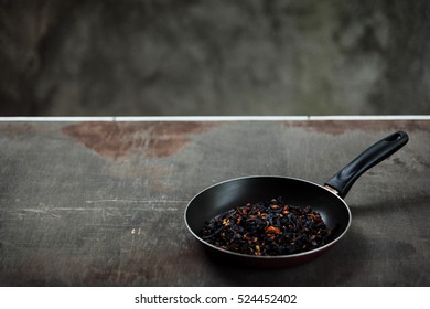 The Failure On Kitchen: Burnt Charred Vegetables. Frying Pan With Refried Black Onion And Overcooked Orange Carrots. Cooking Fail Concept Background With Copy Space.