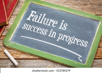 Failure is success in progress - inspirational text on a  slate blackboard with a white chalk and a stack of books against rustic wooden table