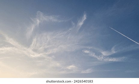 Faint sky in the evening with thin clouds  There were airplanes flying over, emitting a long cloud-like trail of smoke.