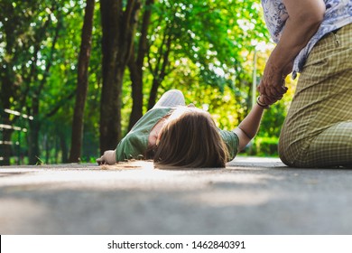 Fainted girl checked by an old woman – Teenager lying on the ground while pulse is checked by an elder citizen - Shutterstock ID 1462840391