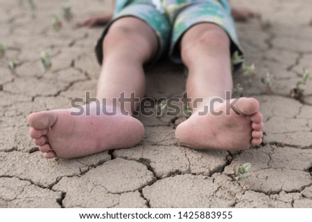 Fainting from heat, dehydration in a child. Children's feet lie on cracked dried earth.