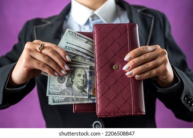 Fair Female Hand Holding A Black Purse With One Hundred Dollar Bills. A Hand Takes Money Out Of A Wallet. Isolated On White Background