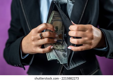 Fair Female Hand Holding A Black Purse With One Hundred Dollar Bills. A Hand Takes Money Out Of A Wallet. Isolated On White Background