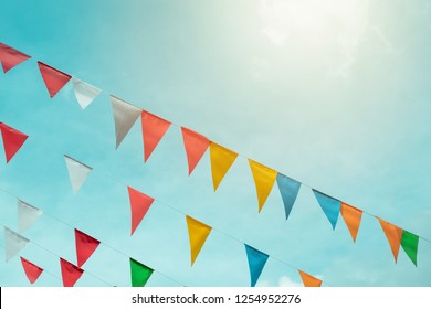Fair flag bunting colorful background hanging on blue sky for fun fiesta party event, summer holiday farm feast celebration, carnival festival event, park or street festa design decoration