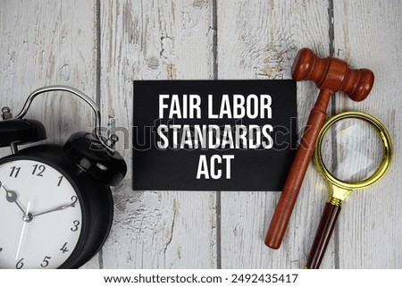 Fair Labor Standards Act text on paper card with alarm clock and wooden judge gavel top view on wooden background