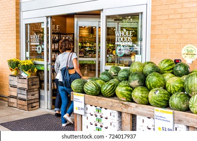 Fairfax, USA - September 8, 2017: female entering Whole Foods Market grocery store building in city in Virginia with autumn displays and watermelons
