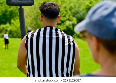 Fairfax, Virginia, USA - May 15, 2022: A Mother Looks Past A Referee Watching Her Son Play During A Boys Flag Football Game.