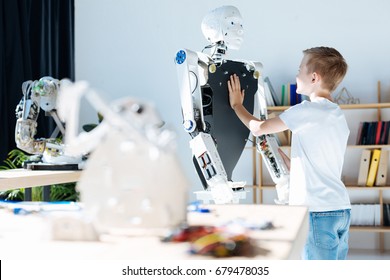 Fair-haired Boy Touching Chest Of A Human Robot