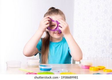 Ein fein gehütetes Kind ohne Milchzahn spielt mit violettem Schleim. Das kleine schöne Kaukasier Mädchen spielt mit vielen Schlägen und lächelt. Spiel Slime Toy.