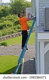 Fairhaven, Massachusetts - June 2 2021: A Technician Works On The Outside Unit Of A Ductless Mini Split Air-conditioning System Mounted On The Wall Of A Building.