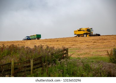 Fairlie, South Canterbury, New Zealand, February 15 2019: A Yellow New Holland Combine Harvester Has Stopped Work Because Of Rain And Sits On The Hilltop