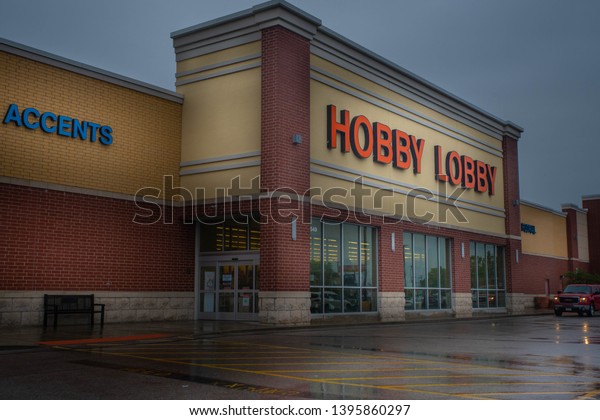 Fairview Heights,\
IL—May 11, 2019; car with headlights on during rain storm drives\
through wet parking lot in front of Hobby Lobby arts and crafts\
store location in strip\
mall