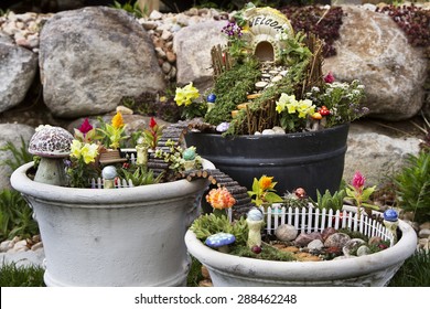 Fairy garden in a flower pot with walking path, wooden bridges and a fairy house. 