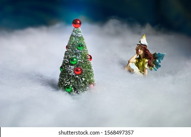 Fairy gazes on Christmas tree in the snow.                           