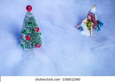 Fairy gazes on Christmas tree in the snow.