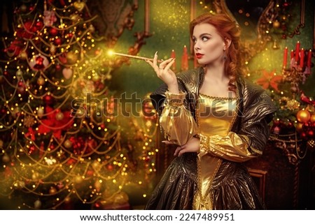 Fairy tales about princesses and miracle. Beautiful red-haired princess sorceress in a rich dress stands in the castle, beautifully decorated for Christmas, and does magic with a magic stick. 