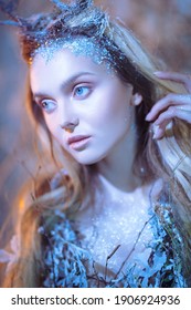 Fairytale character. Close-up portrait of an enchanting forest nymph with clear blue eyes and blonde hair covered with ice. 