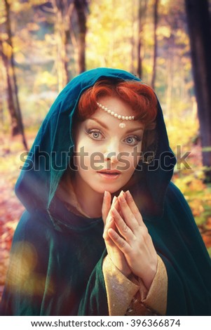 A fairytale fantasy. Red-headed woman in autumn forest. She dressed in renaissance costume. 
