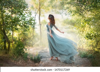 fairy-tale princess in light summer blue turquoise dress on wide path and walks towards wind, graceful dancing girl in image of flower with flying long hem of dress, nymph of bright green forest - Shutterstock ID 1470117269
