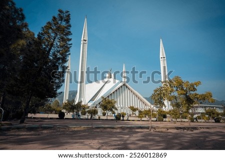 The Faisal Mosque, an iconic structure located in Islamabad, Pakistan. The mosque is notable for its contemporary design, with sharp, angular lines and towering minarets that point towards the sky.