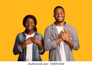 With Faith In Heart. Black Couple Praying With Hands On Chest