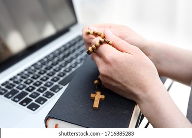 Glaube und Gebet. Eine Frau betet am Rosenkranz. Eine Frau betet auf einem Rosenkranz vor einem Computer.