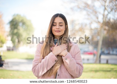 Faithful woman closes eyes and keeps hands on chest near heart, shows her kindness or favour, expresses sincere emotions, being kind hearted and honest. Body language and real feelings concept
