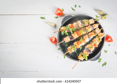 Fajita chicken kebabs, with chicken meat, pepper, chili, tomatoes, onions, lime juice and herbs. In a frying pan, on a white wooden table. Mexican cuisine, a traditional food, Top view, copy space 